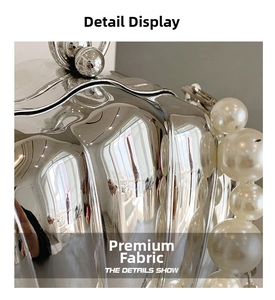 Detailed macro view of silver metallic shell bag surface with elegant pearl handle