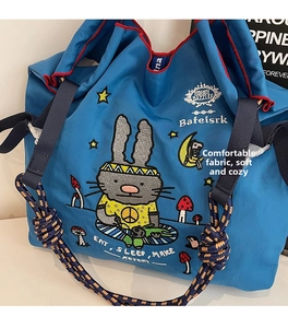 Close-up of blue canvas tote bag with bunny illustration and Bobby Dazzler embroidery