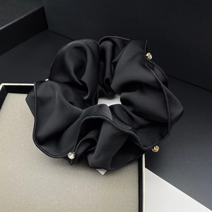 Close-up of black silk scrunchie with rhinestones placed on a premium gift box