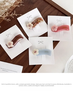 Close-up of four floral acetate hair clips with crystal accents and gold France label