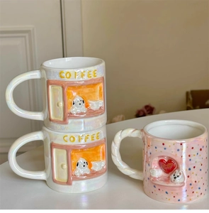 Detail of pearlescent ceramic mugs with embossed puppy designs and coffee lettering