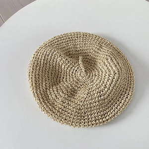Detail of handmade crocheted texture on breathable beige straw beret hat