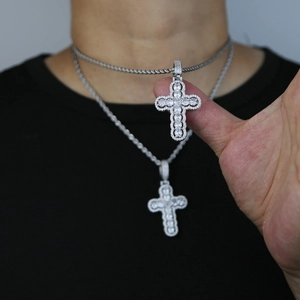 Detailed close-up of hollow silver cross pendant set with sparkling zircon stones