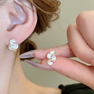 Macro shot of silver wave pleated earrings with matte finish and artistic silk texture