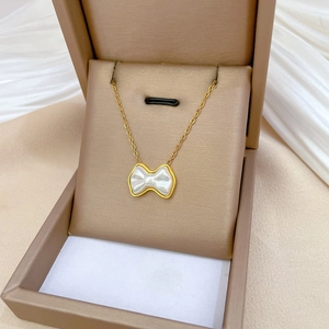 Detail of gold bow necklace with white enamel inlay inside a luxury jewelry box