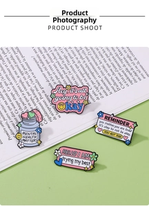 Macro view of pastel enamel pins with mental health quotes on a mint green background
