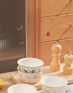 Detail of floral ceramic bowls on a wooden board showing underglaze craft texture