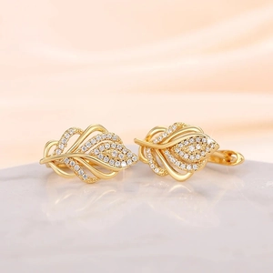 Macro detail of golden leaf-shaped earrings featuring densely inlaid sparkling crystals