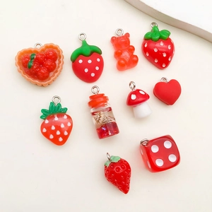 Flat lay di ciondoli in resina rossa con fragole, funghi, cuori e motivi di orsi