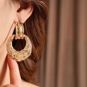 Close-up of golden round earrings with wave texture on a model showing fine details