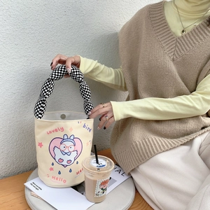 Detail der Canvas-Beuteltasche mit Vogel-Cartoon-Druck und kariertem gepolstertem Griff