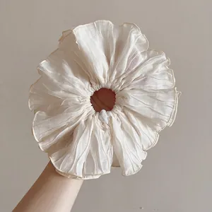Detailed close-up of oversized pleated sheer scrunchie with fine rolled edges in cream color