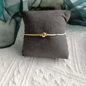 Detail of freshwater pearl bracelet with gold beads on a soft grey jewelry pillow