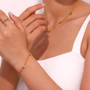 Close-up of 18K gold plated necklace and bracelet set with delicate heart charms on model