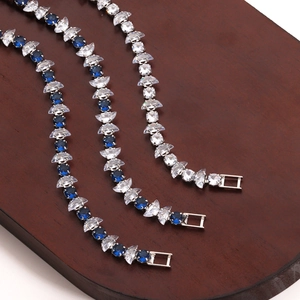 Macro detail of silver-tone bracelets with blue and white zircons on a wooden base