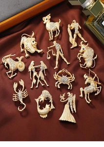Detailed collection of 12 zodiac gold brooches with rhinestones on dark velvet