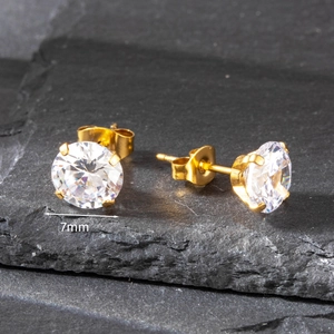 Close-up of 7mm round cubic zirconia stud earring with golden four-prong setting
