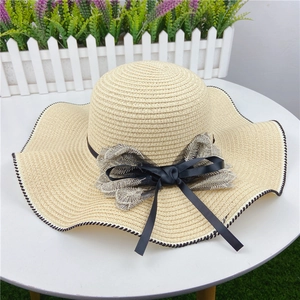 Detail of woven straw hat featuring a black and white wavy edge with elegant double bow