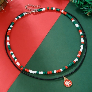 Detail of a double-layer Christmas necklace with red and green beads and a snowflake pendant