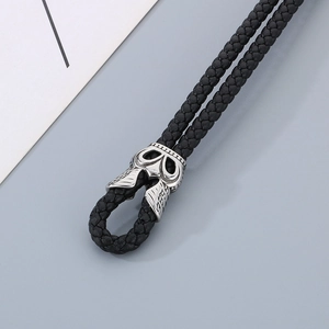 Macro detail of braided black leather cord with silver indian skull metal clasp