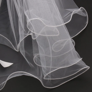 Close-up of elegant white bridal tulle veil with delicate curled edges on black background