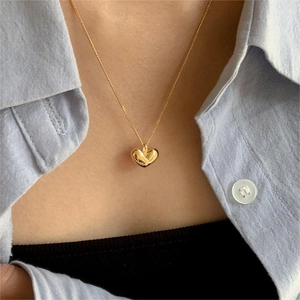 Detailed close-up of a minimalist gold heart pendant necklace worn on a model