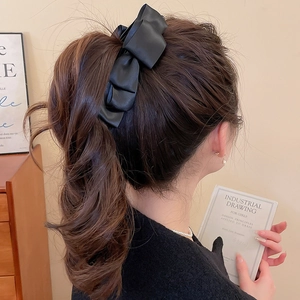 Détail d'un grand nœud papillon noir en satin porté sur d'élégants cheveux ondulés