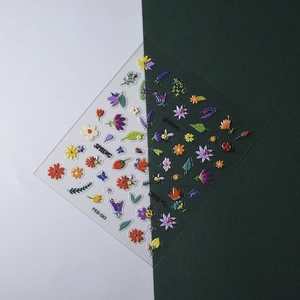 Macro shot of 5D spring floral nail decals with 3D embossed flowers and insects