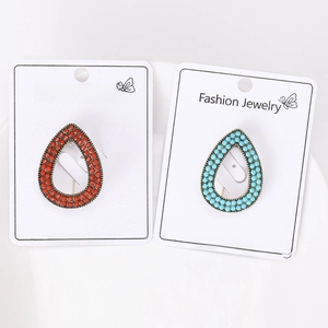 Detailed shot of retro gold water-drop brooches with colorful beads on white packaging