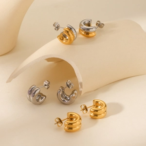 Three pairs of layered 18K gold and silver stainless steel hoop earrings on a stand