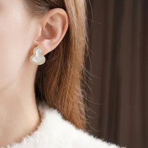 Elegante 18K Gold-Ohrstecker in Kürbisform mit Perlmutt und Zirkonia am Modell getragen