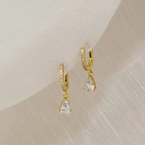 Elegant gold-plated teardrop earrings with cubic zirconia stones on linen texture