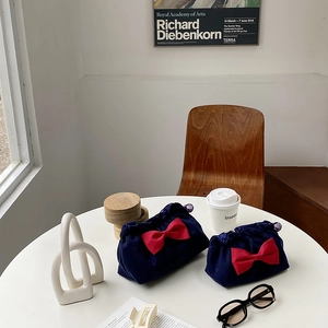 Detail of navy canvas cosmetic bags with large red bows and purple bead clasps