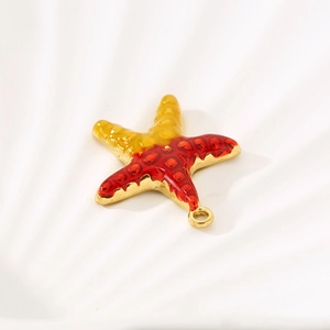Detailed view of a gold starfish pendant with red and yellow enamel on a shell base