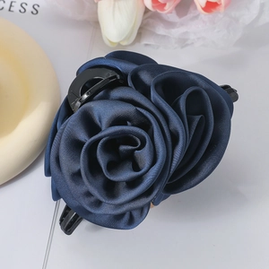 Close-up of elegant dark blue satin rose hair claw clip with glossy fabric texture