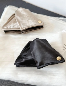 Détail de pinces à cheveux en satin triangle champagne et noir avec boucle dorée élégante
