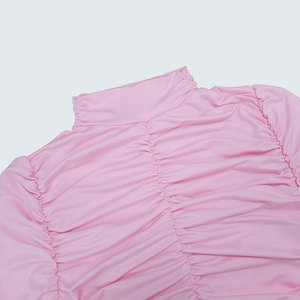 Détail de la robe rose à col montant avec fronces élégantes et textures plissées fines