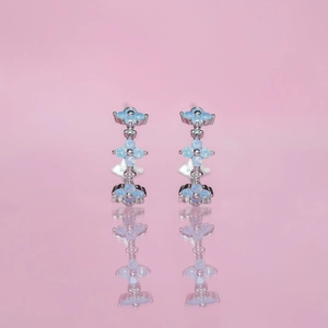 Blue zircon flower earrings set in 18K gold plating on a reflective pink surface