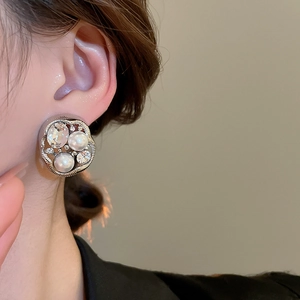 Macro shot of vintage silver earrings with irregular pearls and crystals on female model