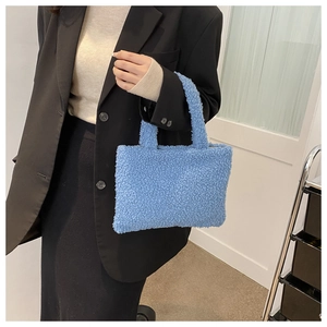 Close-up of fluffy blue plush handbag with double handles styled with a black suit jacket