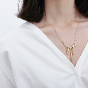 Gold plated 925 sterling silver liquid wax pendant necklace worn by a model in white
