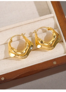 Detail of wavy 18K gold plated hoop earrings displayed in a luxury wooden jewelry box