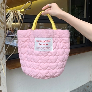 Détail du sac à main rose matelassé en cœurs avec poignée jaune et écusson brodé enfant