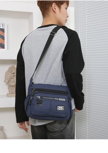 Detail view of adjustable black nylon strap and zipper pulls on blue crossbody bag