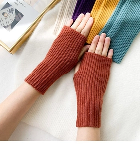 Detail of rust red fingerless knitted gloves showing ribbed texture and stretch material