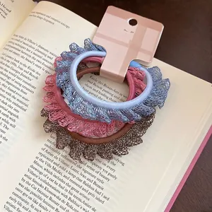 Lot de trois chouchous élastiques en dentelle bleue, rose et marron sur un livre de style vintage