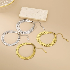 Detailed view of gold and silver braided snake chain bracelets on a textured stone base