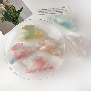 Flat lay of marble pattern hair claw clips in various colors with elegant tulip decor