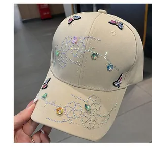 Close-up of beige baseball cap featuring intricate colorful rhinestone butterfly patterns