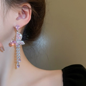 Detail of pink butterfly earrings with sparkling cubic zirconia tassels on a model